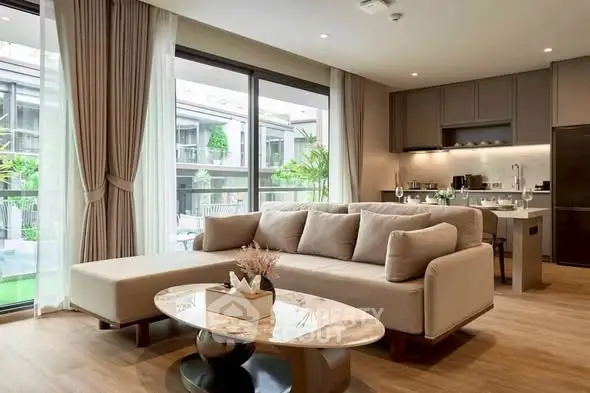 Luxurious modern living room with open kitchen and large windows overlooking greenery.