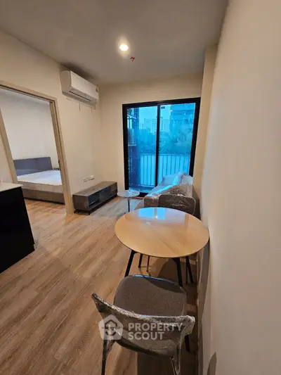 Modern apartment with cozy living area and bedroom view, featuring wooden flooring and natural light.