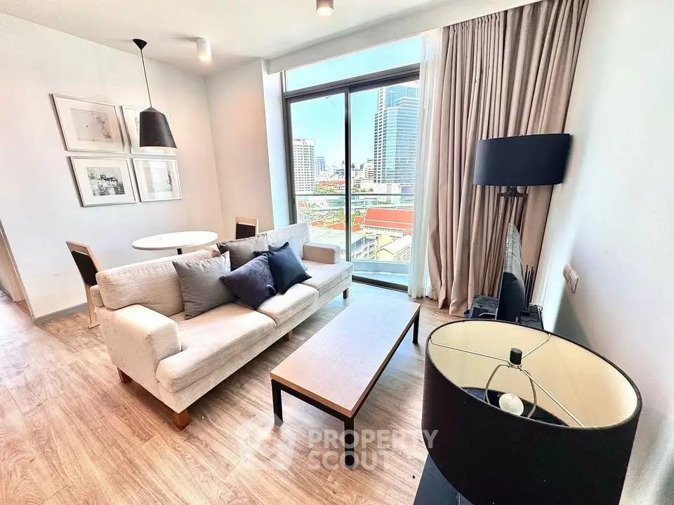 Modern living room with city view, featuring stylish furniture and large windows.