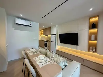 Modern open-plan living room with dining area and kitchen, featuring sleek furniture and built-in appliances.