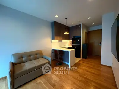 Modern studio apartment with open kitchen and cozy living area, featuring sleek wooden flooring.