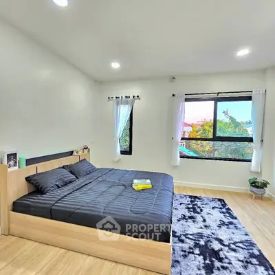 Spacious bedroom with modern decor and large windows offering natural light