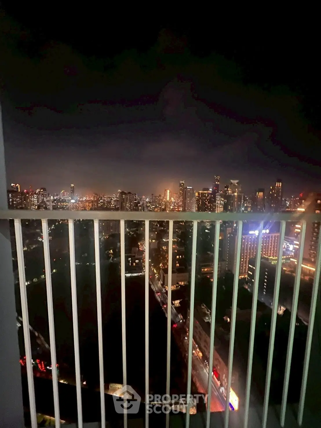 Stunning city skyline view from a high-rise balcony at night, showcasing vibrant urban lights.