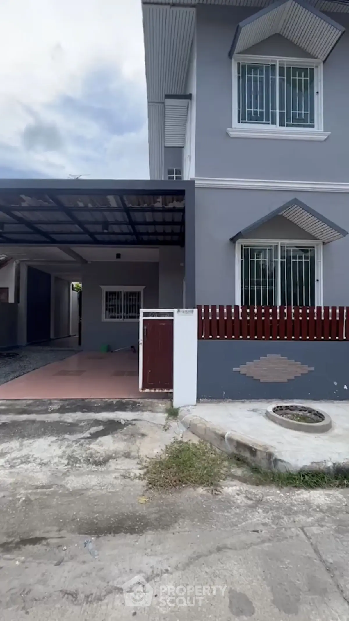 Modern two-story house with carport and gated entrance in a suburban neighborhood.