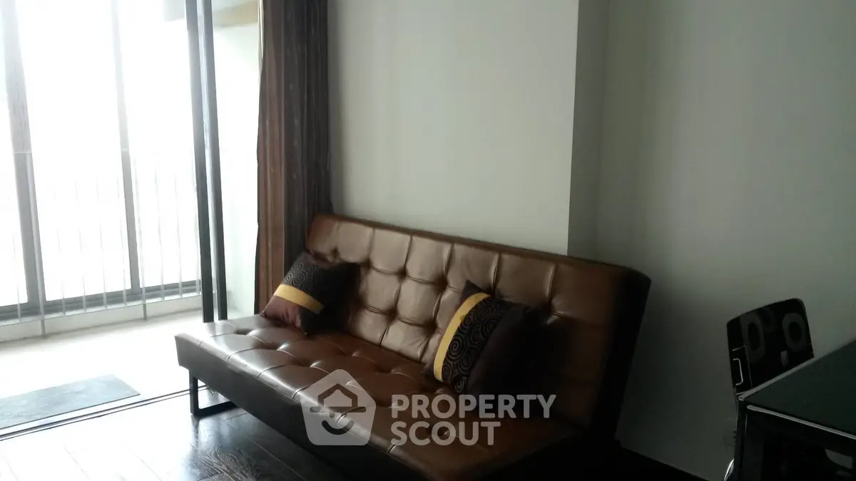 Modern living room with stylish brown leather sofa and balcony access.