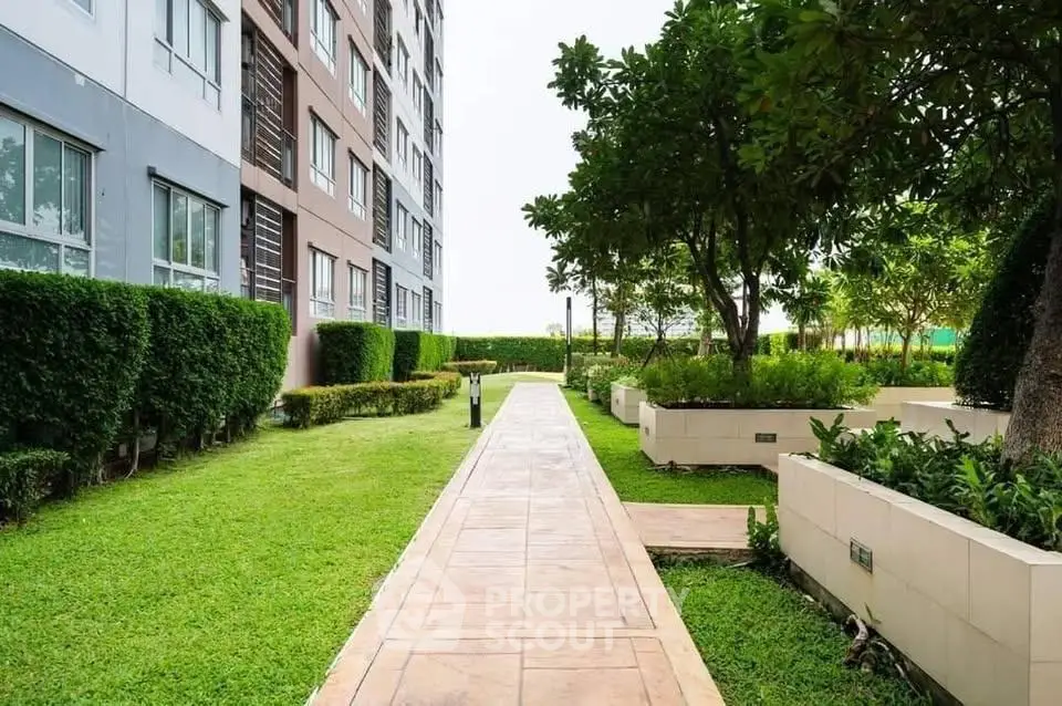 Beautiful garden pathway beside modern apartment building with lush greenery.
