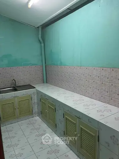 Simple kitchen with tiled countertops and pastel green cabinets