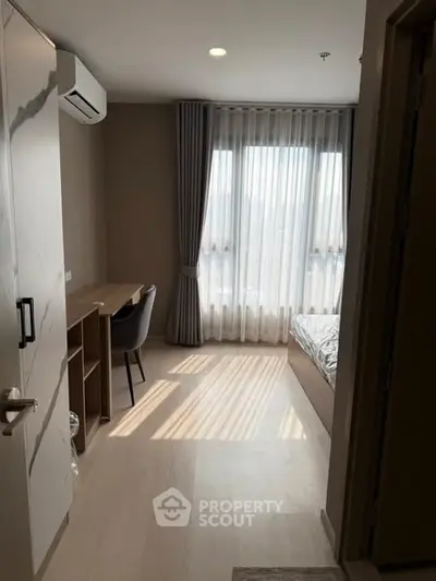 Cozy bedroom with natural light, modern furniture, and elegant curtains in a stylish apartment.