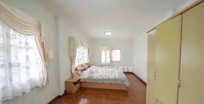 Spacious bedroom with elegant curtains and wooden flooring in a cozy home.