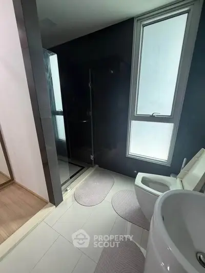 Modern bathroom with sleek black accents and large window for natural light.
