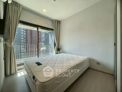 Modern bedroom with large window and city view, featuring a comfortable mattress and sleek design.