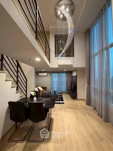Luxurious modern living room with high ceilings and elegant chandelier in a stylish duplex apartment.