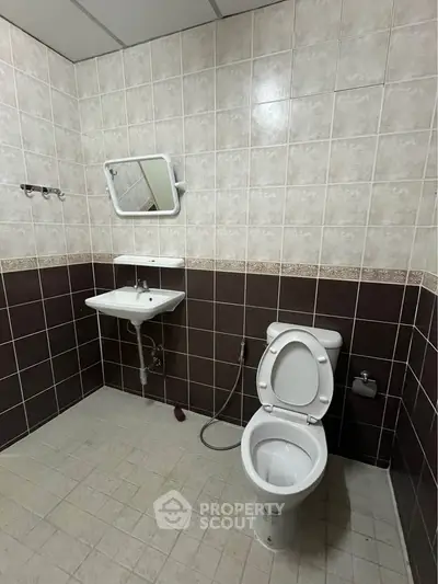 Spacious bathroom with modern fixtures and tiled walls, featuring a toilet and sink.