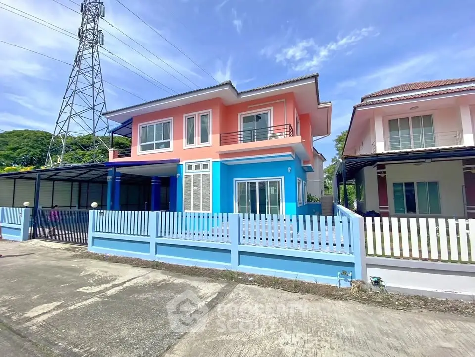 Charming two-story house with colorful facade and fenced yard in a serene neighborhood.