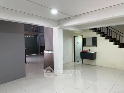 Spacious open-plan interior with modern staircase and sleek tile flooring, ideal for versatile living arrangements.