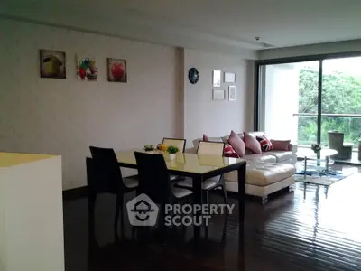 Spacious living room with modern dining area and large windows overlooking greenery.