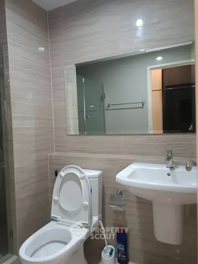 Modern bathroom with sleek fixtures and neutral tones, featuring a glass shower and elegant sink.