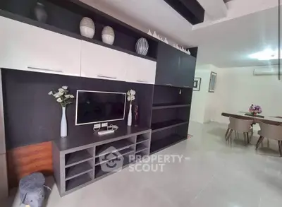 Modern living room with sleek entertainment center and dining area, perfect for stylish urban living.