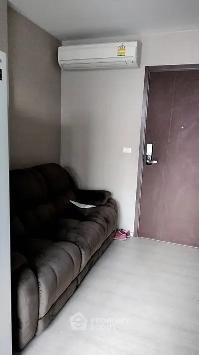 Cozy living room with plush sofa and modern air conditioning unit, perfect for relaxation.