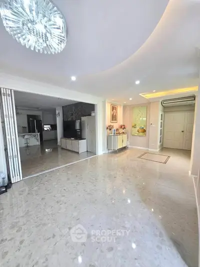 Spacious living room with elegant marble flooring and modern lighting in a luxurious home.