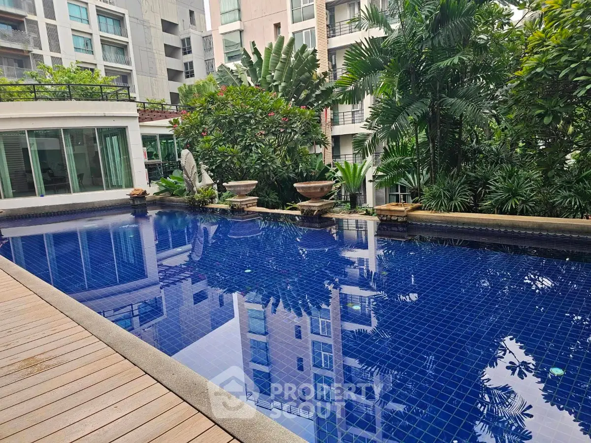 Luxurious condominium pool surrounded by lush greenery and modern architecture, perfect for relaxation and leisure.