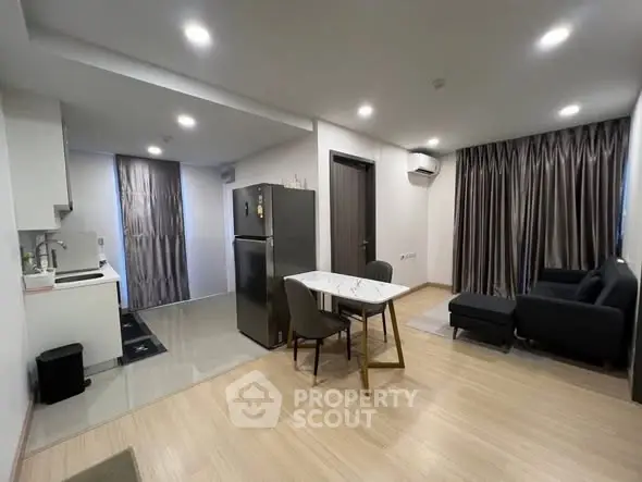 Modern open-plan living room with kitchen and dining area, featuring sleek furniture and contemporary design.