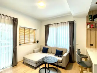 Modern living room with cozy sofa and stylish decor, featuring natural light and elegant curtains.