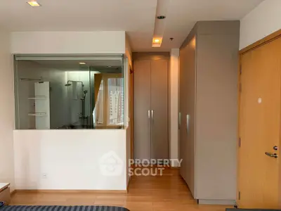 Modern bedroom with glass-walled bathroom and sleek storage solutions