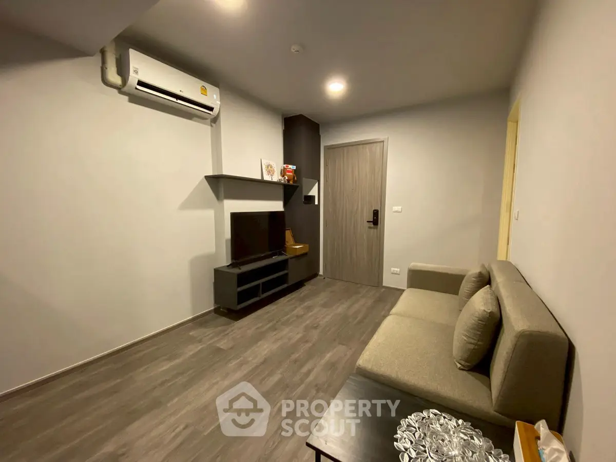 Modern living room with sleek design and air conditioning, featuring a comfortable sofa and stylish flooring.