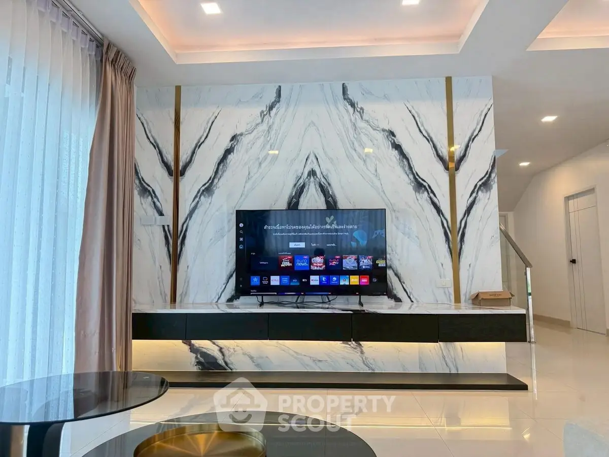 Luxurious living room with modern TV setup and elegant marble wall design.