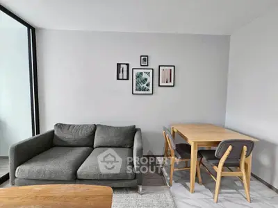 Modern living room with stylish gray sofa and wooden dining set, perfect for cozy gatherings.