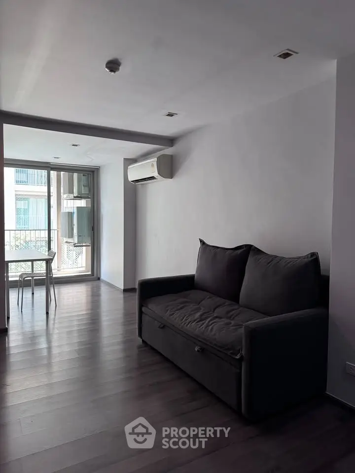 Spacious living room with modern sofa and large windows offering natural light.