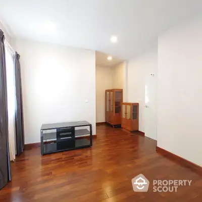 Spacious and well-lit living room with polished hardwood flooring and minimalist decor, ready for personalization.