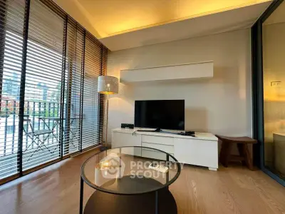 Modern living room with large windows and stylish decor, featuring a TV and cozy seating area.