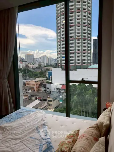 Spacious bedroom with stunning city view from large window in high-rise apartment.