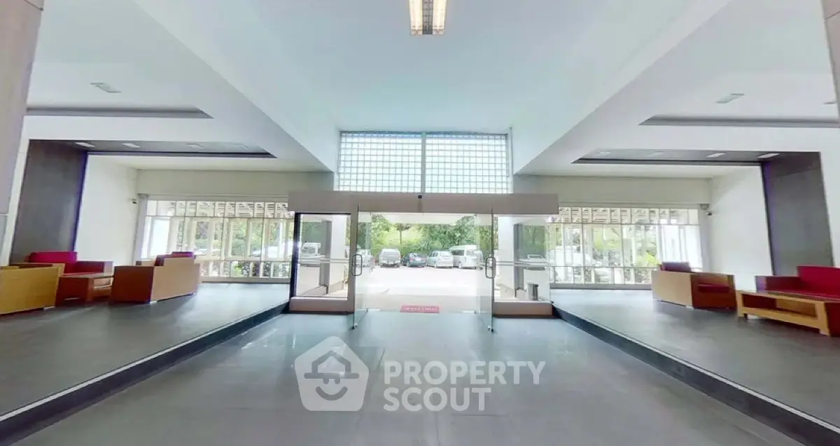 Spacious modern building entrance with glass doors and seating area, ideal for welcoming guests.