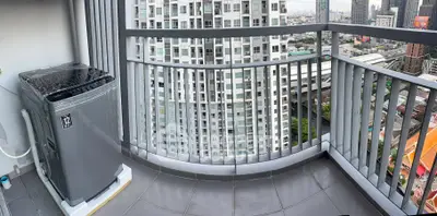 Spacious balcony with city view and washing machine in modern high-rise apartment.