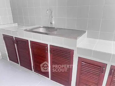 Modern kitchen with sleek stainless steel sink and stylish wooden cabinets.