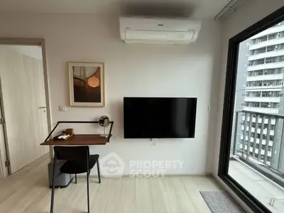 Modern study area with wall-mounted TV and balcony view in a stylish apartment.