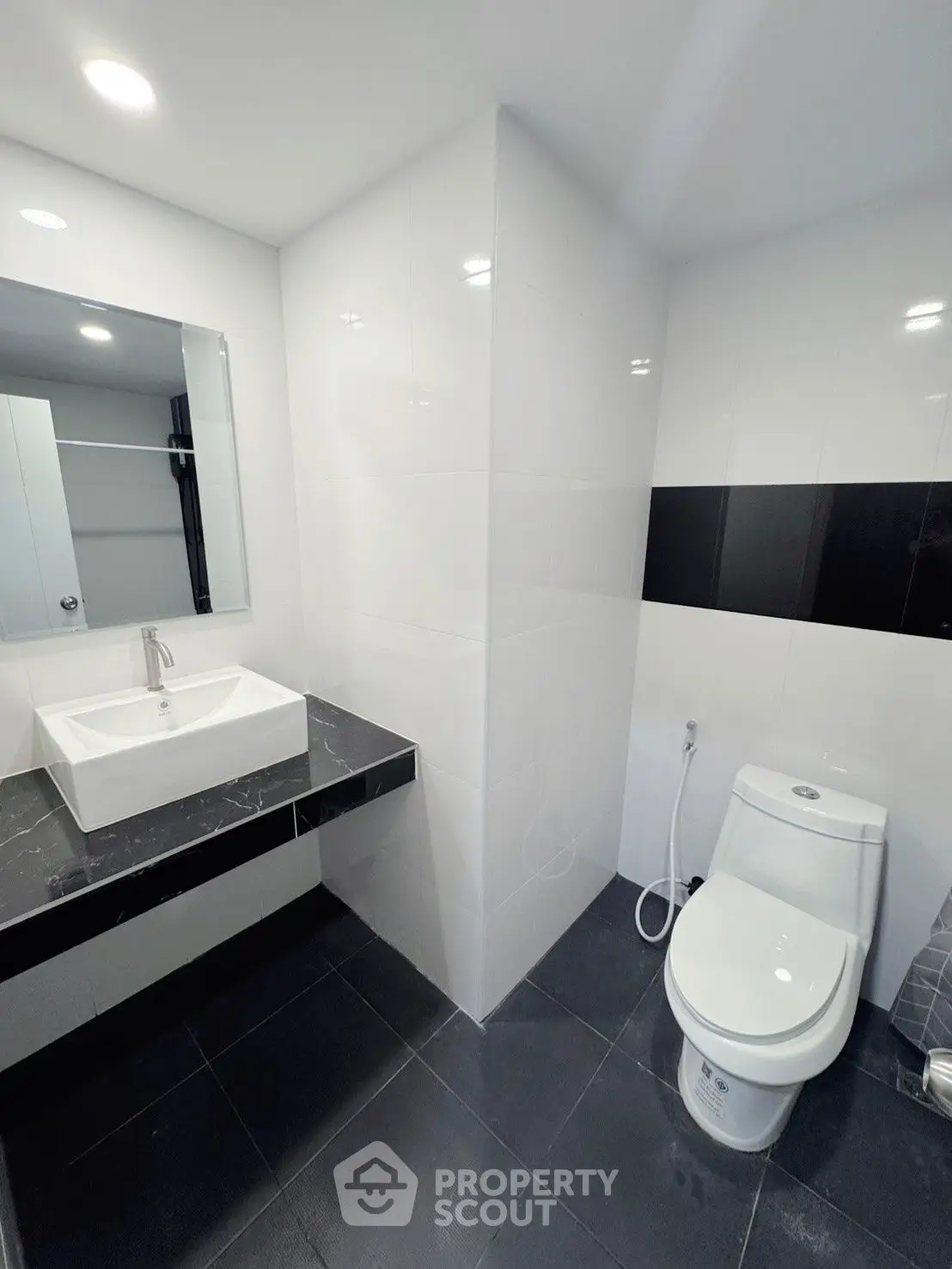 Modern bathroom with sleek black and white design, featuring a stylish sink and toilet.