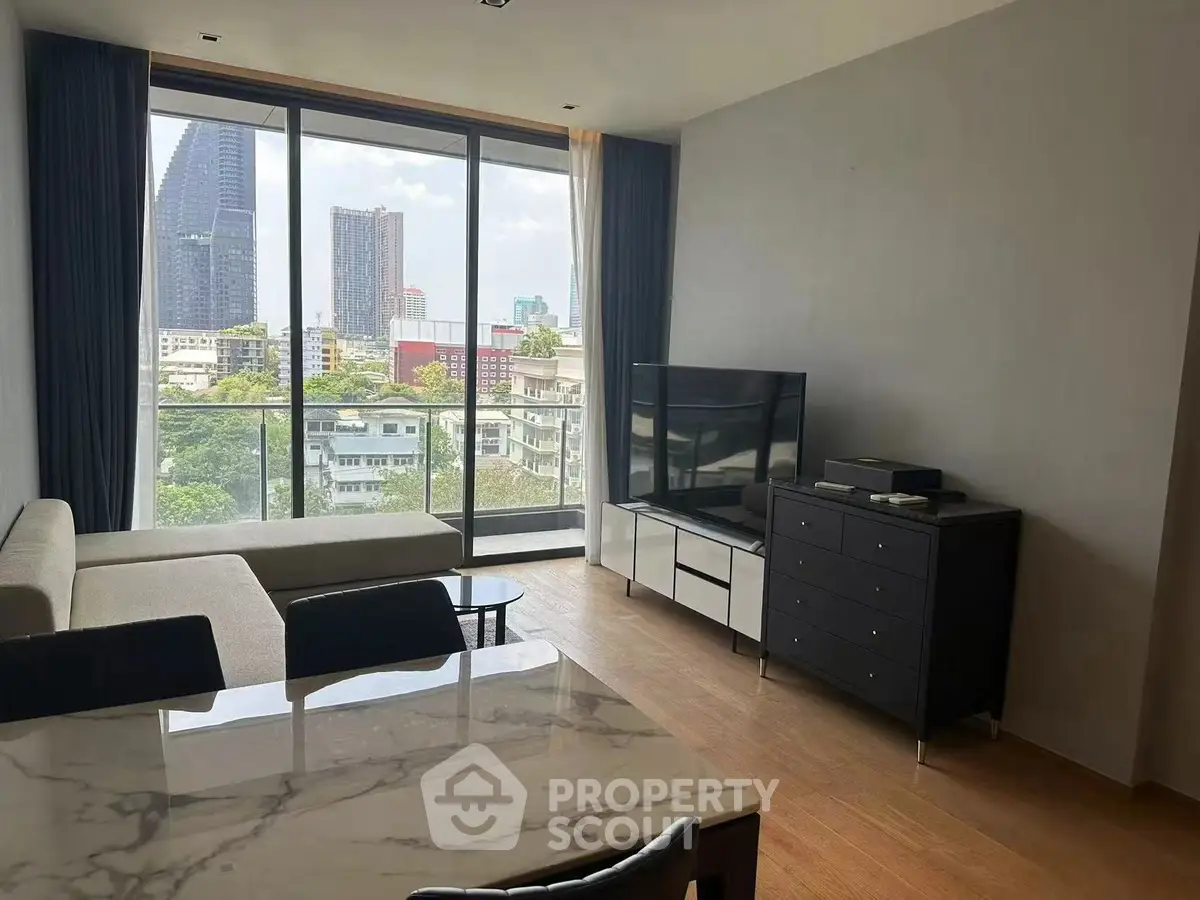 Modern living room with city view, featuring sleek furniture and floor-to-ceiling windows.