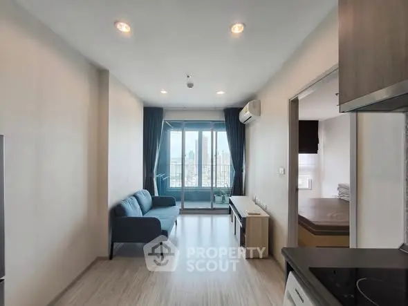 Modern apartment with open layout, featuring a cozy living room and city view balcony.