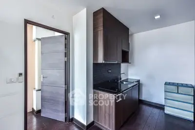 Modern kitchen with sleek cabinetry and dark wood flooring in a compact layout