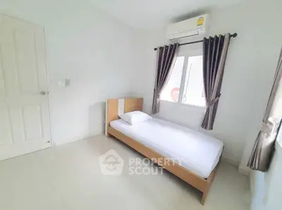 Bright and minimalist bedroom with single bed and air conditioning, perfect for a cozy retreat.