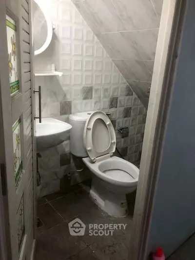 Compact under-stair bathroom with modern tiles and essential fixtures.