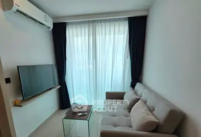 Cozy living room with modern sofa, wall-mounted TV, and large window with curtains.