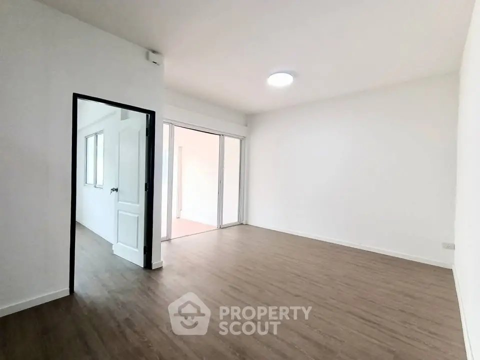 Spacious empty room with wooden flooring and bright lighting, ideal for customization.