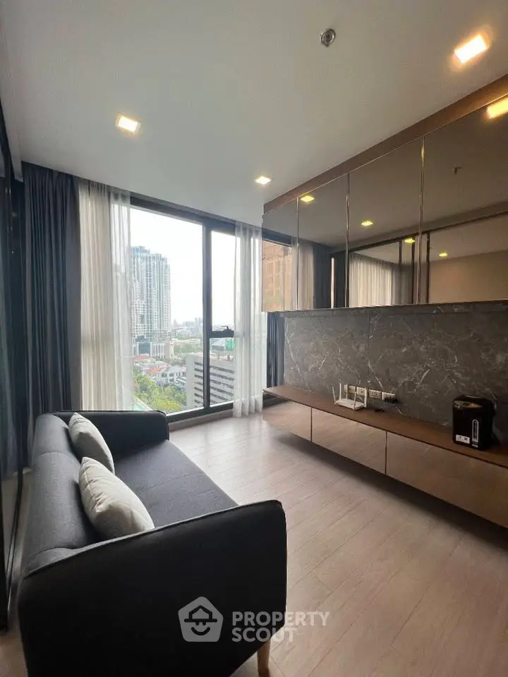 Modern living room with city view, featuring sleek furniture and large windows for natural light.