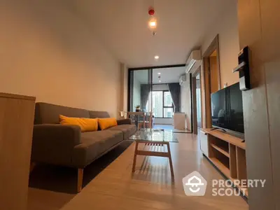 Modern living room with cozy sofa and TV, open layout leading to dining area with city view.