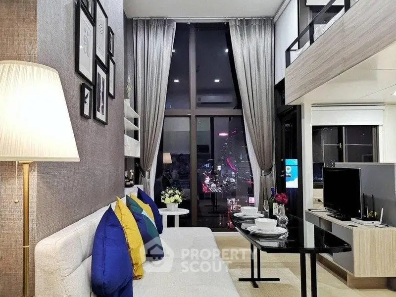 Modern loft-style living room with high ceilings and city view, featuring elegant decor and vibrant cushions.
